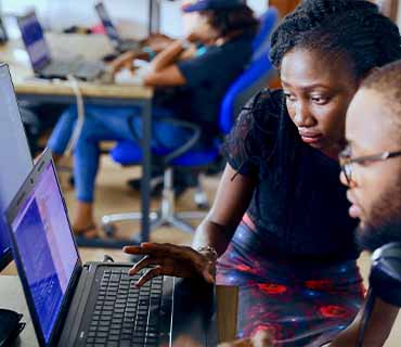 a man and women looking to laptop screen